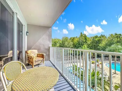 a balcony with a table and chairs and a pool at Beautiful Orlando Lakefront Condo 5 MINUTES FROM DISNEY in Orlando