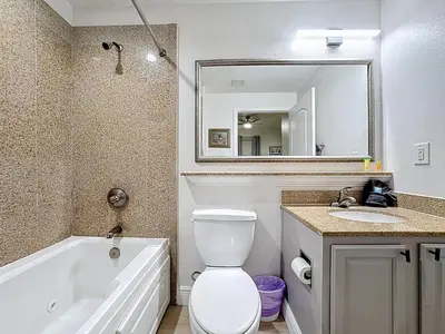a bathroom with a toilet and a sink and a mirror at Beautiful Orlando Lakefront Condo 5 MINUTES FROM DISNEY in Orlando