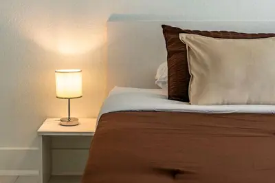 a bed with a lamp on a side table at Luxury Studio Gem 10min to Disney Pool and Amenities in Kissimmee