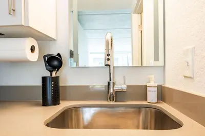 a stainless steel sink in a kitchen with a mirror at Modern New APT in perfect Location only 10min to Disney in Kissimmee