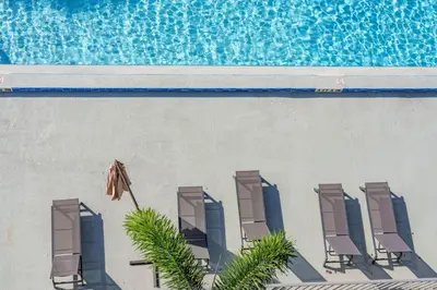 a group of chairs and an umbrella in front of a swimming pool at Modern New APT in perfect Location only 10min to Disney in Kissimmee