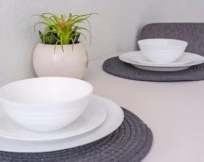 a table with white bowls and plates and a potted plant at Modern New APT in perfect Location only 10min to Disney in Kissimmee