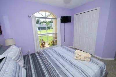 a bedroom with purple walls and a bed with a window at Family Escape Close to parks in Orlando