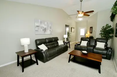a living room with black leather furniture and a ceiling fan at Family Escape Close to parks in Orlando
