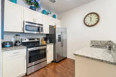 a kitchen with stainless steel appliances and a clock on the wall at Amazing 3BDR House near Disney 12102 in Kissimmee