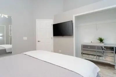 a white bedroom with a bed and a flat screen tv at 4 Bedroom with Pool near to Disney in Kissimmee