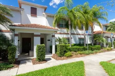 a white house with palm trees in front of it at 4 Bedrooms3 Bathrooms at Storey Lake Resort in Kissimmee