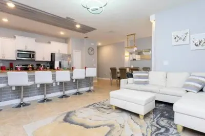 a living room with white furniture and a kitchen at 4 Bedrooms3 Bathrooms at Storey Lake Resort in Kissimmee