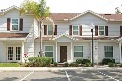 a white house with a palm tree in front of it at Your VIP Home near Disney 25107 in Kissimmee