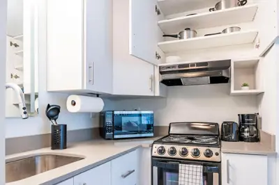 a kitchen with white cabinets and a stove and a sink at Sleek and Luxury Studio near Parks with Free Parking in Kissimmee