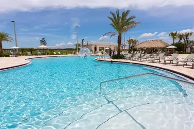 a large swimming pool with chairs and palm trees at Your 5BDR house with pool - 4959 in Kissimmee