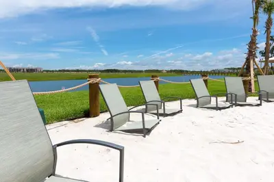 a row of chairs sitting on the sand near the water at Amazing 4BDR with pool near Disney - 4914 in Kissimmee