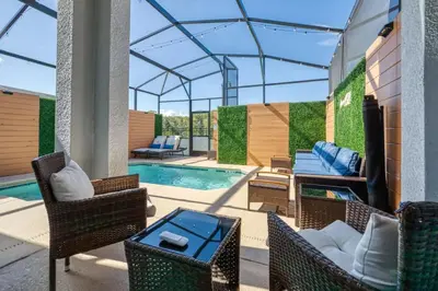 a patio with chairs and a swimming pool at Casa Temática c/ Piscina no Storey Lake in Kissimmee