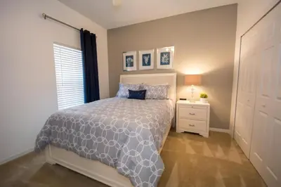 a bedroom with a bed and a nightstand and a window at Villa Bella - 4 Bedrooms in Kissimmee