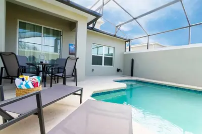 a swimming pool with a table and chairs next to a house at Casa 5 Quartos com Piscina e Tema Disney in Kissimmee