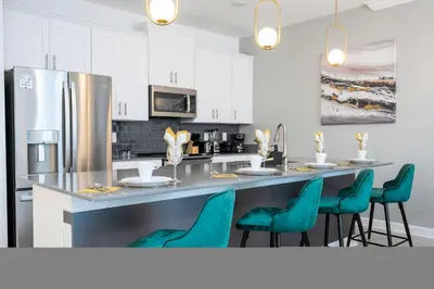 a kitchen with a counter with chairs and a refrigerator at Magical Stay Mickey and Harry Potter Rooms in Kissimmee