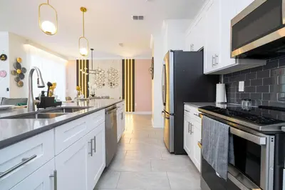 a kitchen with white cabinets and black appliances at Magical Stay Mickey and Harry Potter Rooms in Kissimmee