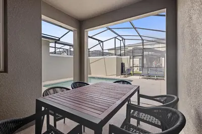 a patio with a table and chairs and a pool at New Home 04 Bedrooms At Storey Lake in Kissimmee