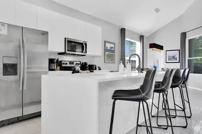 a kitchen with a counter and four bar stools at 5BR Kissimmee Home Pool and Game Room Fun in Kissimmee