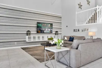 a living room with a couch and a tv on a wall at 5BR Kissimmee Home Pool and Game Room Fun in Kissimmee