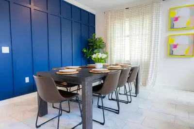 a dining room table with chairs and a blue wall at Fantasy Stay in 5 bed at Storey Lake in Kissimmee