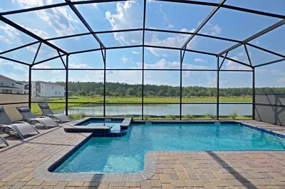 a swimming pool with chairs and a large glass house at 4213 - Lakeside Retreat in Kissimmee