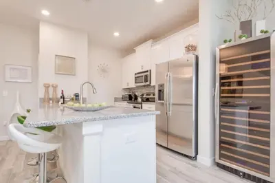 a white kitchen with a counter and a refrigerator at Viva o Luxo – 5 Quartos e Piscina no Resort in Kissimmee