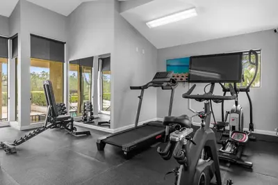 a room with a gym with a treadmill and a tv at 14531 Damai in Orlando