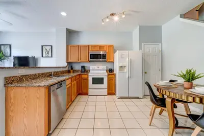 a kitchen with a table and a white refrigerator at Comfy Townhome Minutes from Disney in Orlando