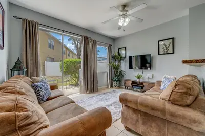 a living room with two couches and a flat screen tv at Comfy Townhome Minutes from Disney in Orlando