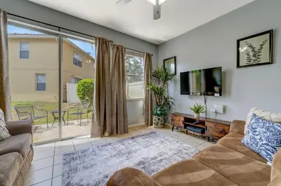 a living room with a couch and a flat screen tv at Comfy Townhome Minutes from Disney in Orlando