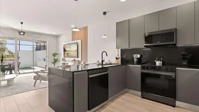 a kitchen with black appliances and a living room at Upstay-Luxury 3BR Home w Private Pool & Games Room in Orlando