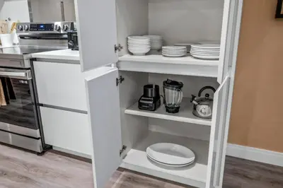 a kitchen with white cupboards with plates and dishes at Elegant Orlando Getaway Close To Disney in Kissimmee