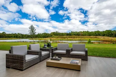 a patio with wicker furniture and a view of a lake at Elegant Orlando Getaway Close To Disney in Kissimmee