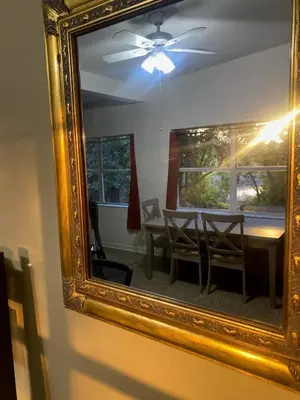 a mirror reflecting a dining room table with a ceiling fan at Orlando 3BR | Hot Tub + Parking + Pets in Orlando