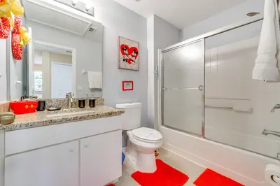 a white bathroom with a toilet and a shower at 10 Mi to Disney Parks Resort Retreat with Patio in Kissimmee