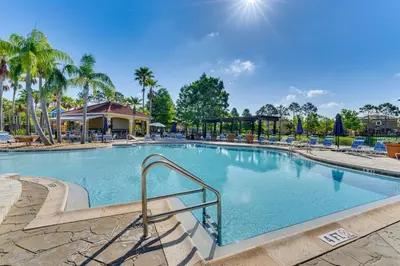 a large swimming pool with chairs and palm trees at 10 Mi to Disney Parks Resort Retreat with Patio in Kissimmee