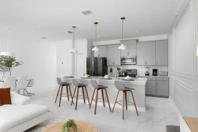 a kitchen with white cabinets and a bar with stools at Townhome 4Q Storey Lake c/ Piscina Privada in Kissimmee
