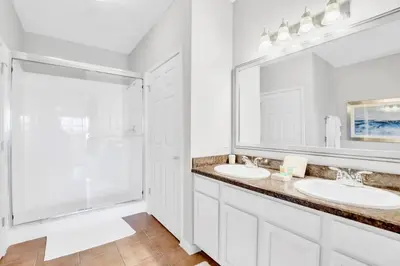 a white bathroom with two sinks and a shower at Upstay Modern 3BR Getaway w Pool in Orlando