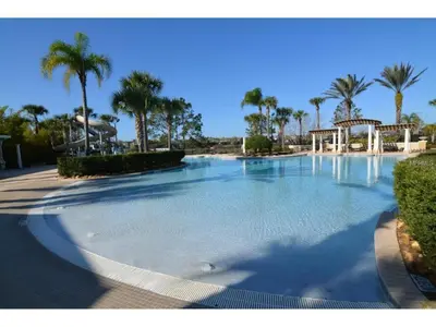 a large swimming pool with palm trees in a resort at Water Park & Fantastic Pool only Minutes To Walt Disney World's Front Gate!!! in Orlando