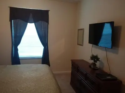 a bedroom with a bed and a tv and a window at Water Park & Fantastic Pool only Minutes To Walt Disney World's Front Gate!!! in Orlando