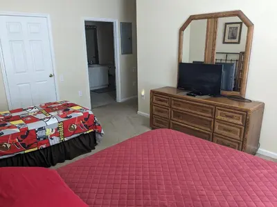 a bedroom with a bed and a dresser with a mirror at Water Park & Fantastic Pool only Minutes To Walt Disney World's Front Gate!!! in Orlando