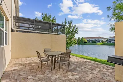 a patio with a table and chairs next to a body of water at Amazing 4 Bedrooms- Near Disney in Kissimmee