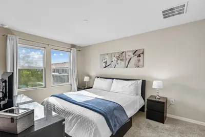 a bedroom with a large bed and two windows at Amazing 4 Bedrooms- Near Disney in Kissimmee
