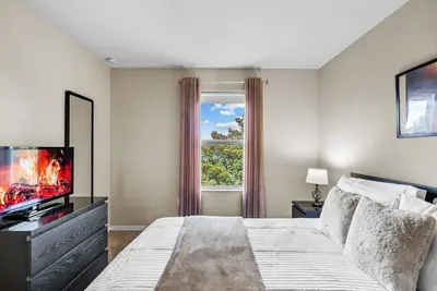 a bedroom with a bed and a tv and a window at Amazing 4 Bedrooms- Near Disney in Kissimmee