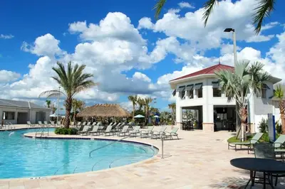 a resort pool with chairs and a building at Casa c/ piscina privativa a 10 min da Disney in Kissimmee