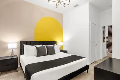 a bedroom with a large bed and a yellow wall at Upstay Bella Vida Resort - Resort-Style 12BR Villa in Kissimmee