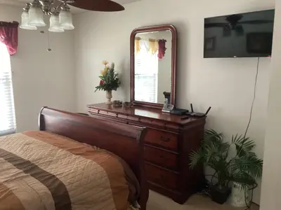 a bedroom with a bed and a mirror on a dresser at Plutospad in Orlando