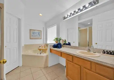 a bathroom with a tub and a sink and a mirror at Spacious Emerald Home - Pool and Lanai Near Disney in Kissimmee
