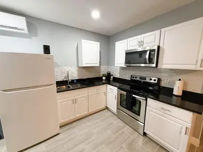a kitchen with white appliances and white cabinets at Cozy Modern Studio in Orlando